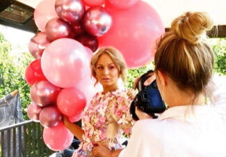 Angeliqa Jonsson som fotar en kvinna i blommig klänning och många stora rosa ballonger på en terass