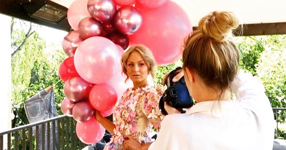Angeliqa Jonsson som fotar en kvinna i blommig klänning och många stora rosa ballonger på en terass