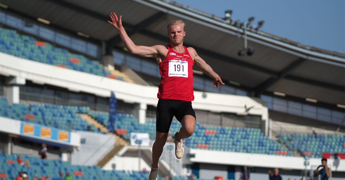 Viktor Pettersson under friidrottstävling, i luften mitt i ett längdhopp