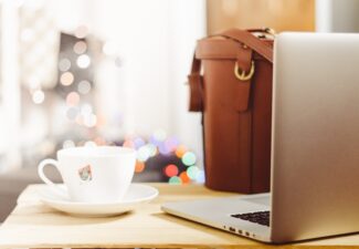 Laptop, kaffekopp och väska i kafémiljö
