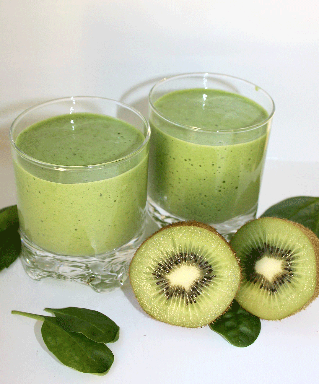 Grön smoothie i fina glas dekorerade med kiwi och bladspenat