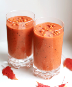 Orange smoothie i fina glas dekorerade med röda höstlöv