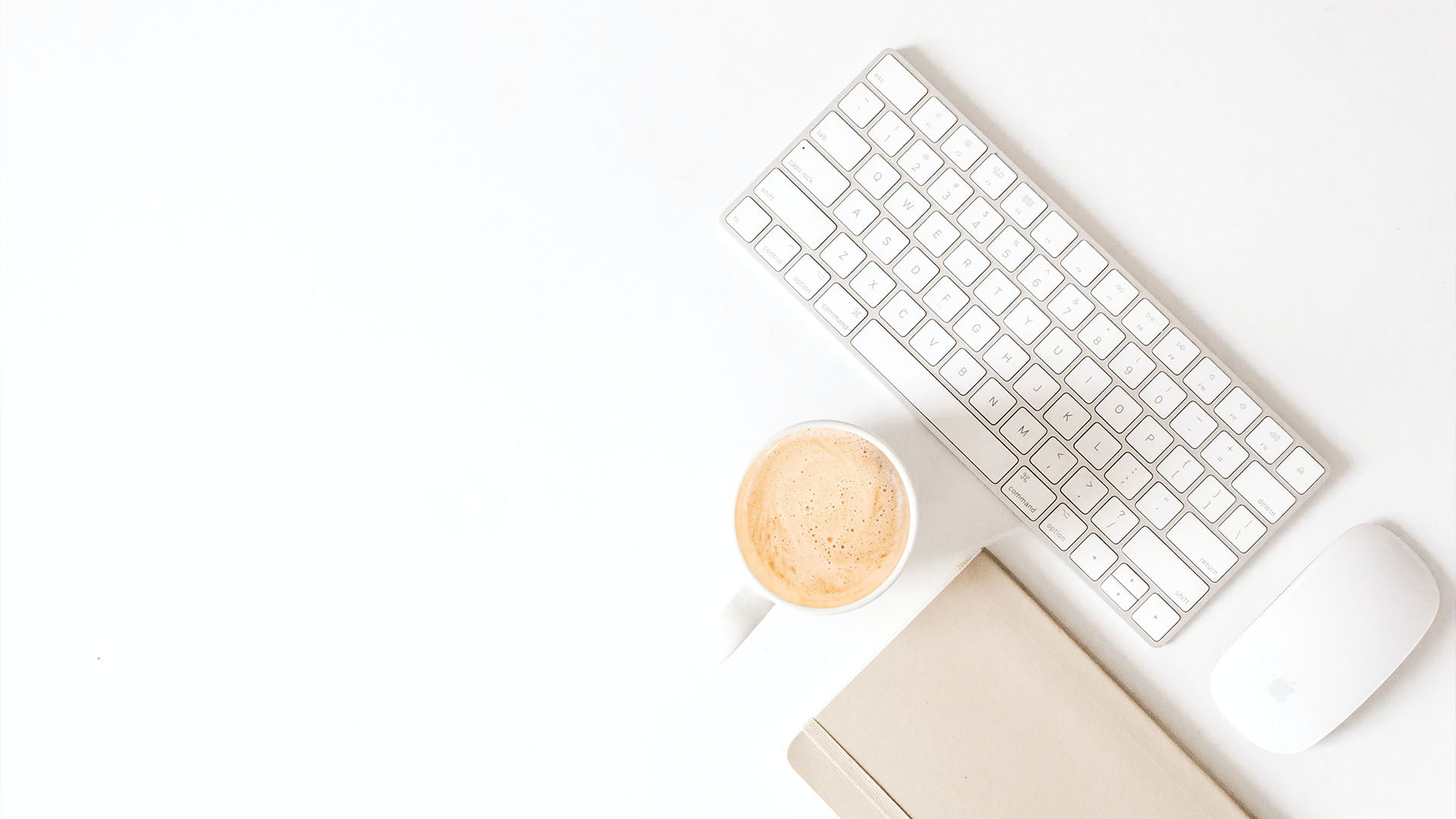 Stilleben med vitt tangentbord, vit datormus, anteckningsblock och kaffekopp på vit yta