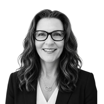 Porträttfoto på utbildningsledaren Ingela Rickander som arbetar på Affärshögskolan. En kvinna med långt hår, glasögon och en vit skjorta under en mörk kavaj ler mot kameran. Bilden är svartvit och framhäver en professionell men vänlig framtoning.
