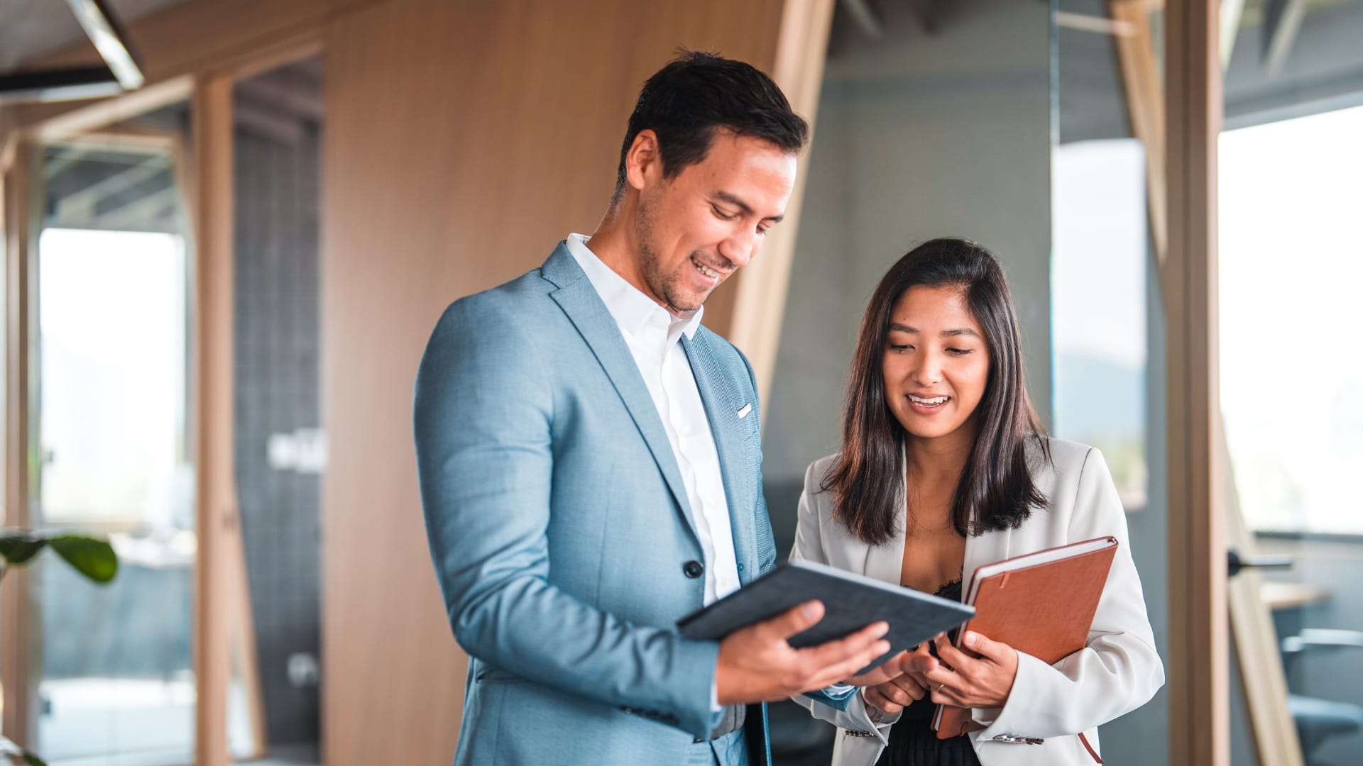 Två personer i ljus kontorsmiljö samtalar och tittar på en surfplatta. Bilden symboliserar LIA och samarbetet mellan student och handledare.